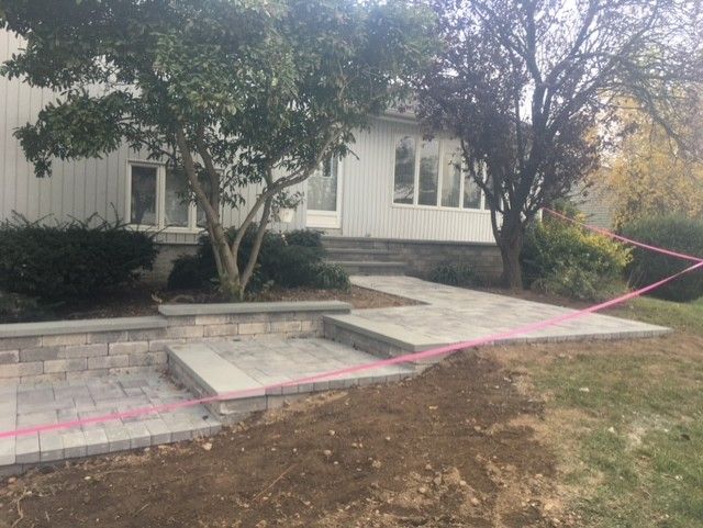 A brick walkway is being built in front of a house.