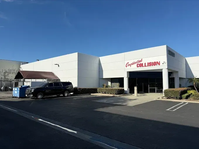 Exterior of a Chevrolet Collision repair shop with a black SUV parked outside under a clear blue sky