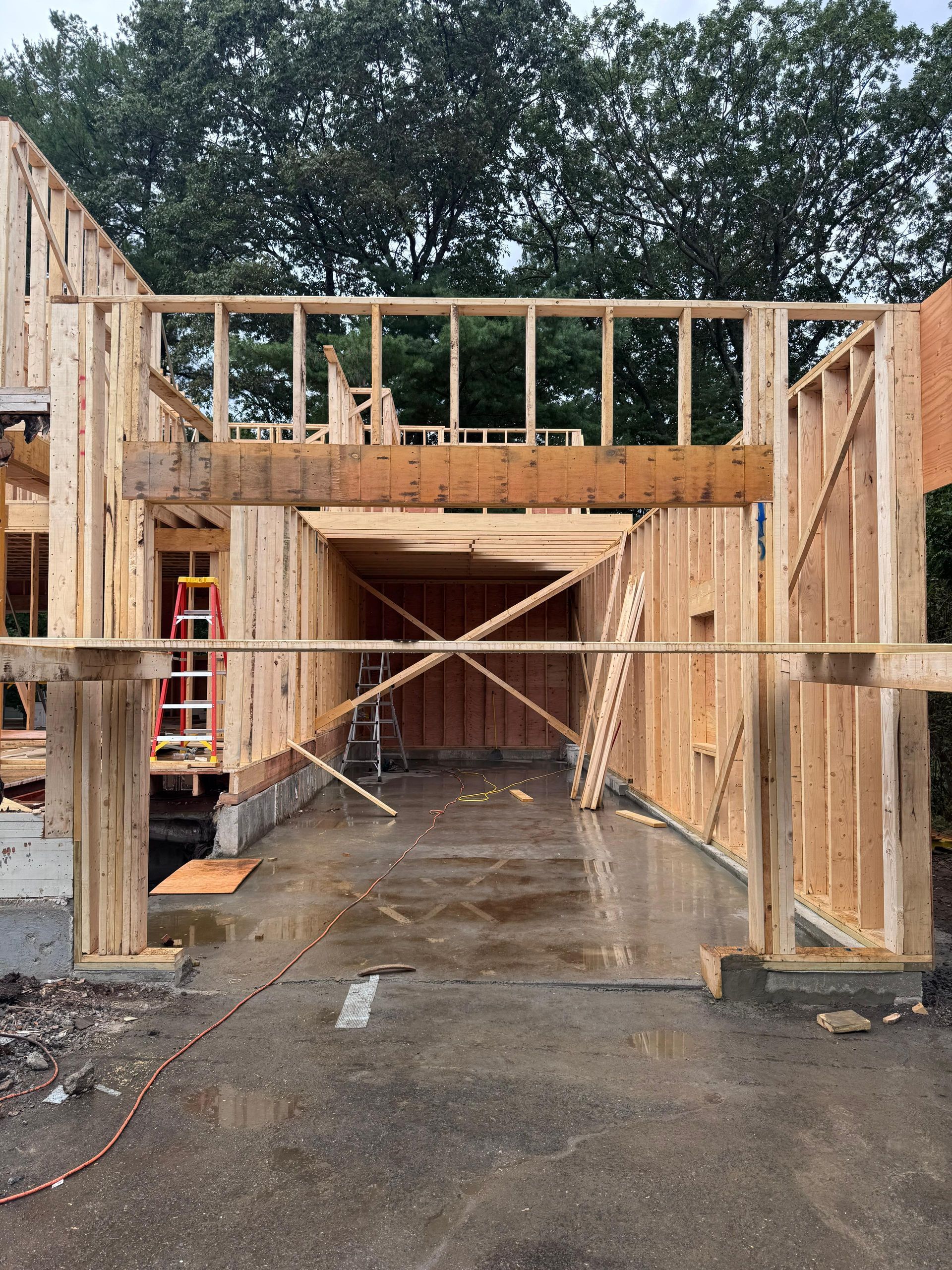 Wooden framing of a residential garage construction site featuring an open doorway and exposed wall studs.