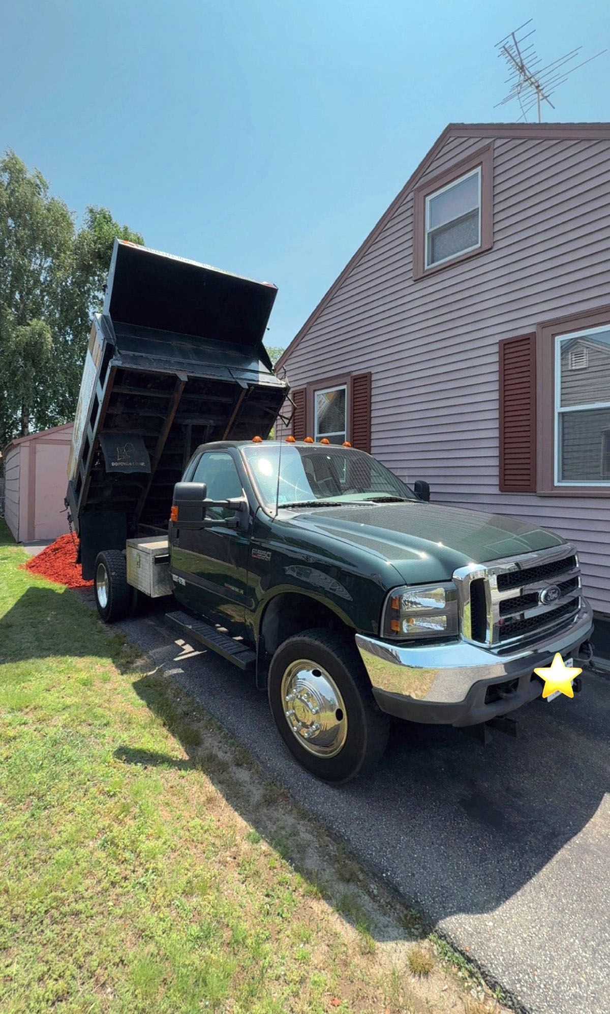 A dump truck with bed raised, unloading landscaping products