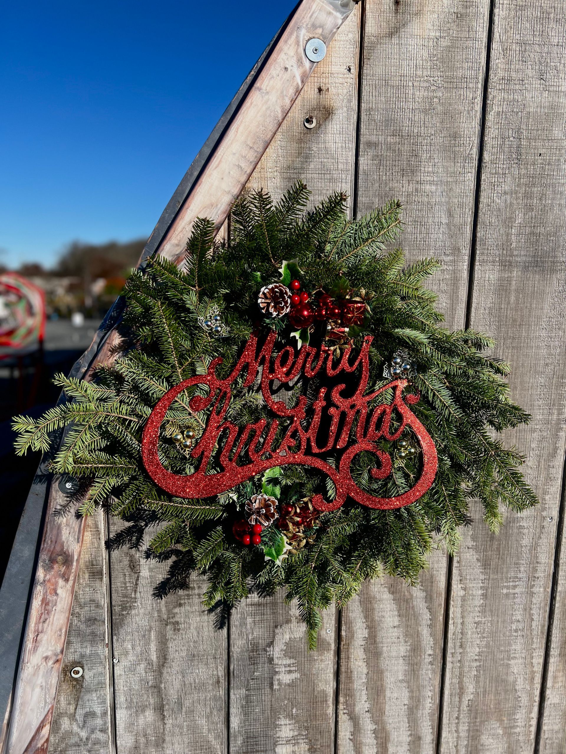 A christmas wreath is hanging on a wooden wall.