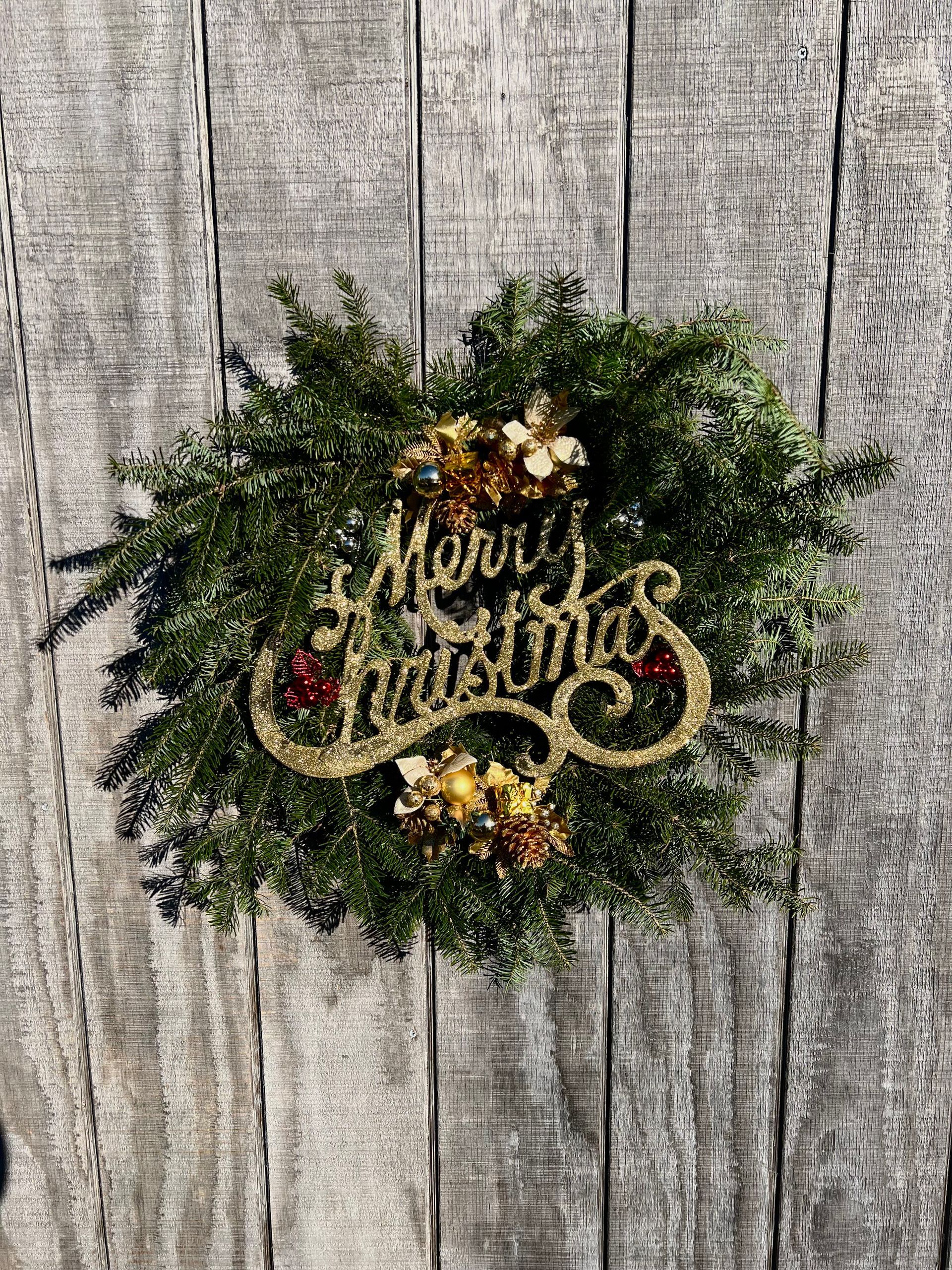 A christmas wreath is hanging on a wooden wall.