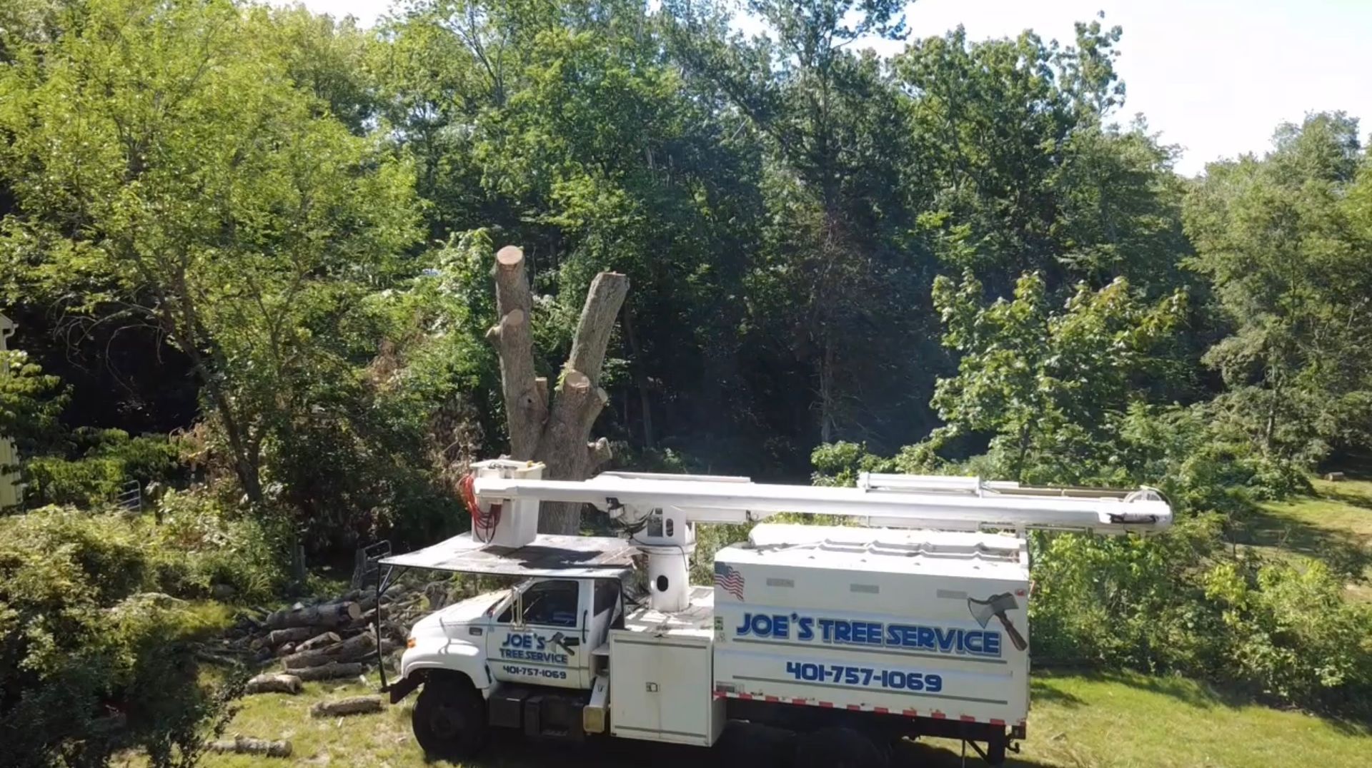 White utility truck with bucket lift parked by trees, labeled “Joe’s Tree Service”