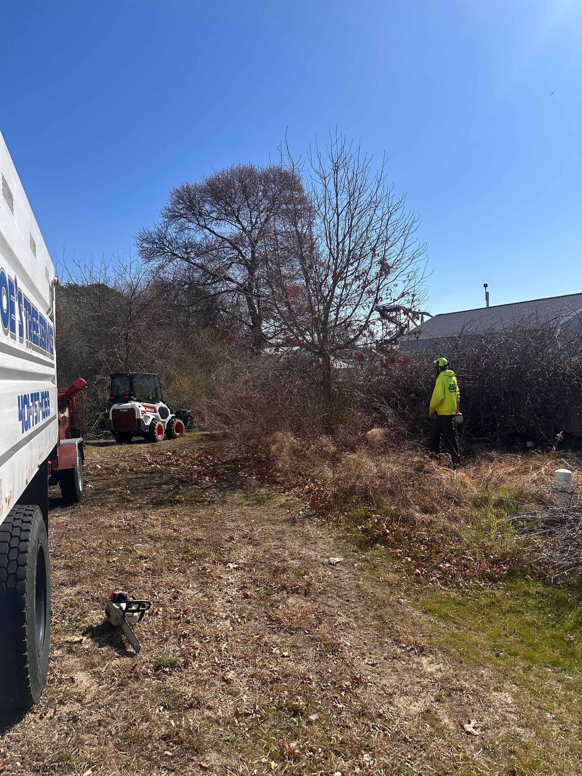 A man in a yellow vest is standing next to a truck in a field.