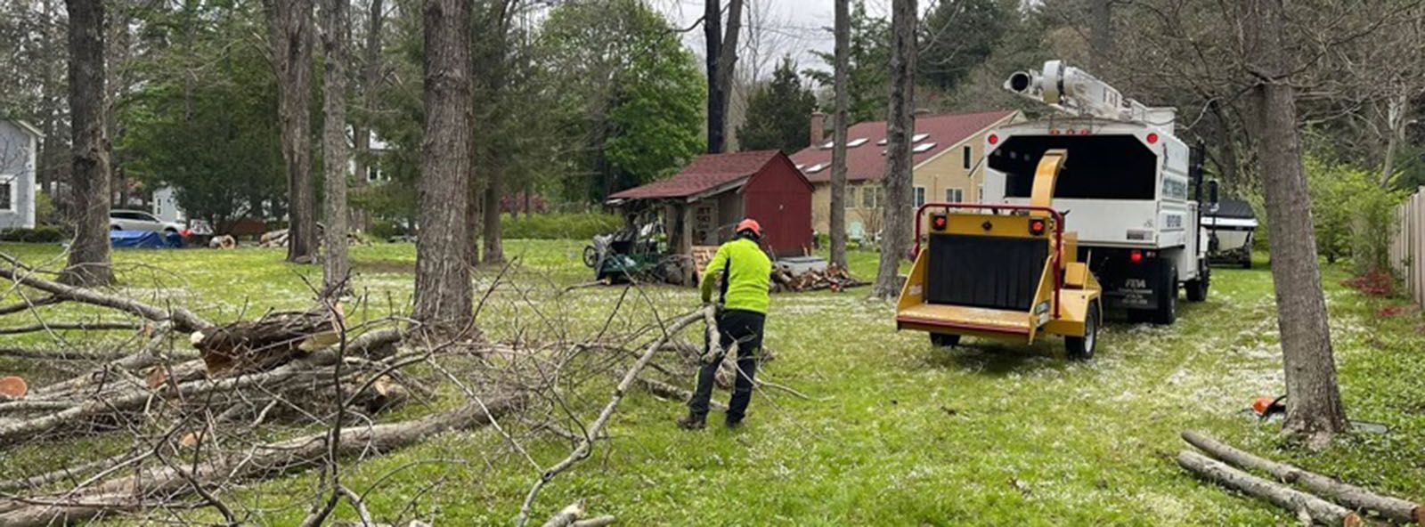 A man is standing in front of a tree chipper in a yard