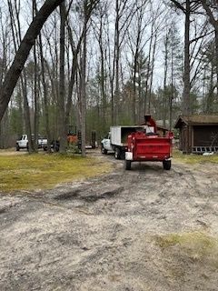 A red dump truck is parked in a dirt lot next to a white truck