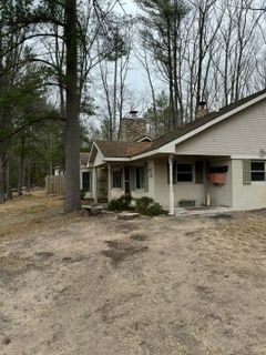 A small white house with a porch in the middle of a forest