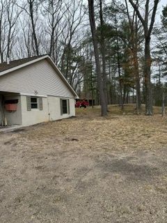 A white house is sitting in the middle of a field surrounded by trees