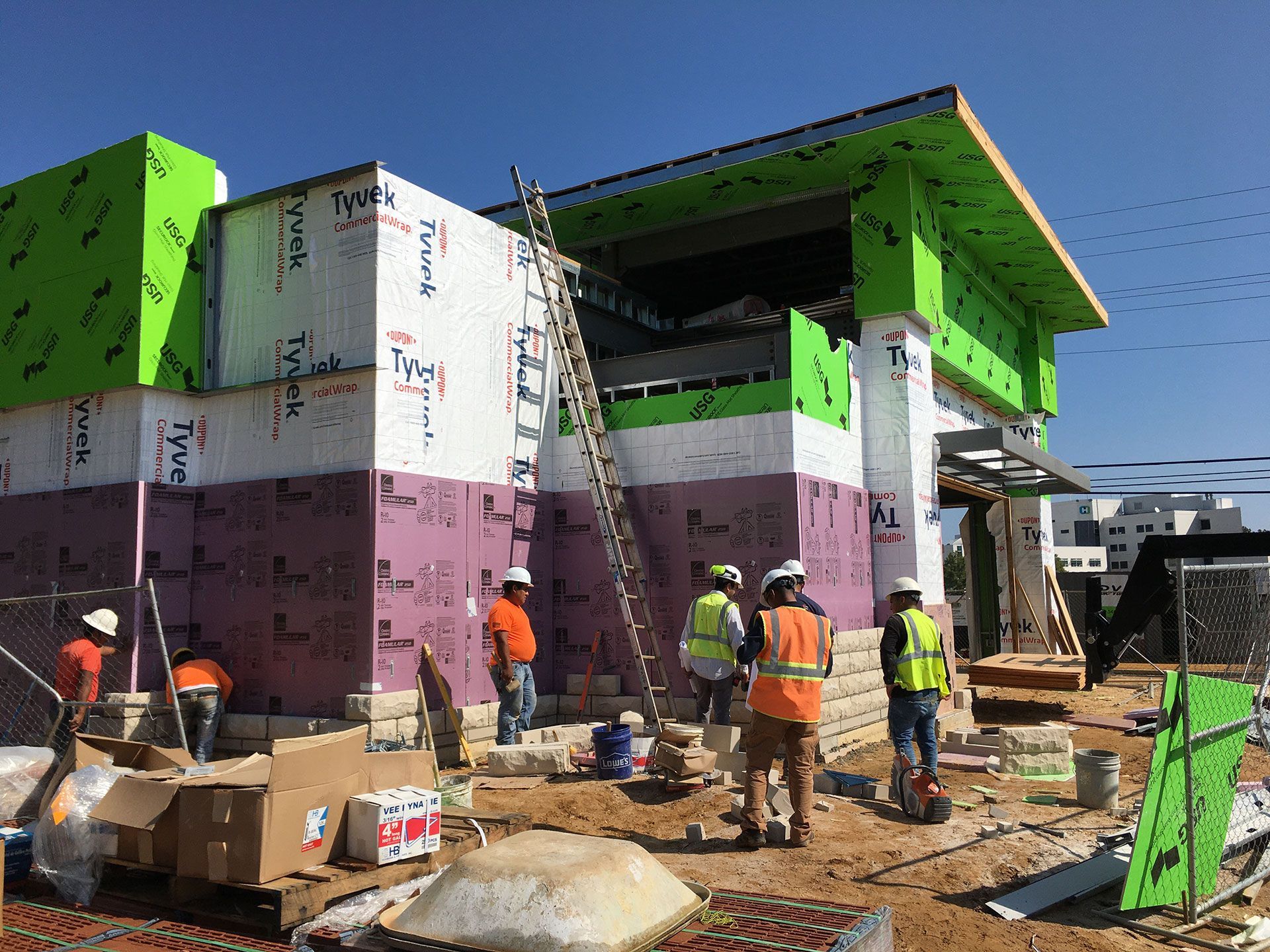 A group of construction workers are standing in front of a building under construction.