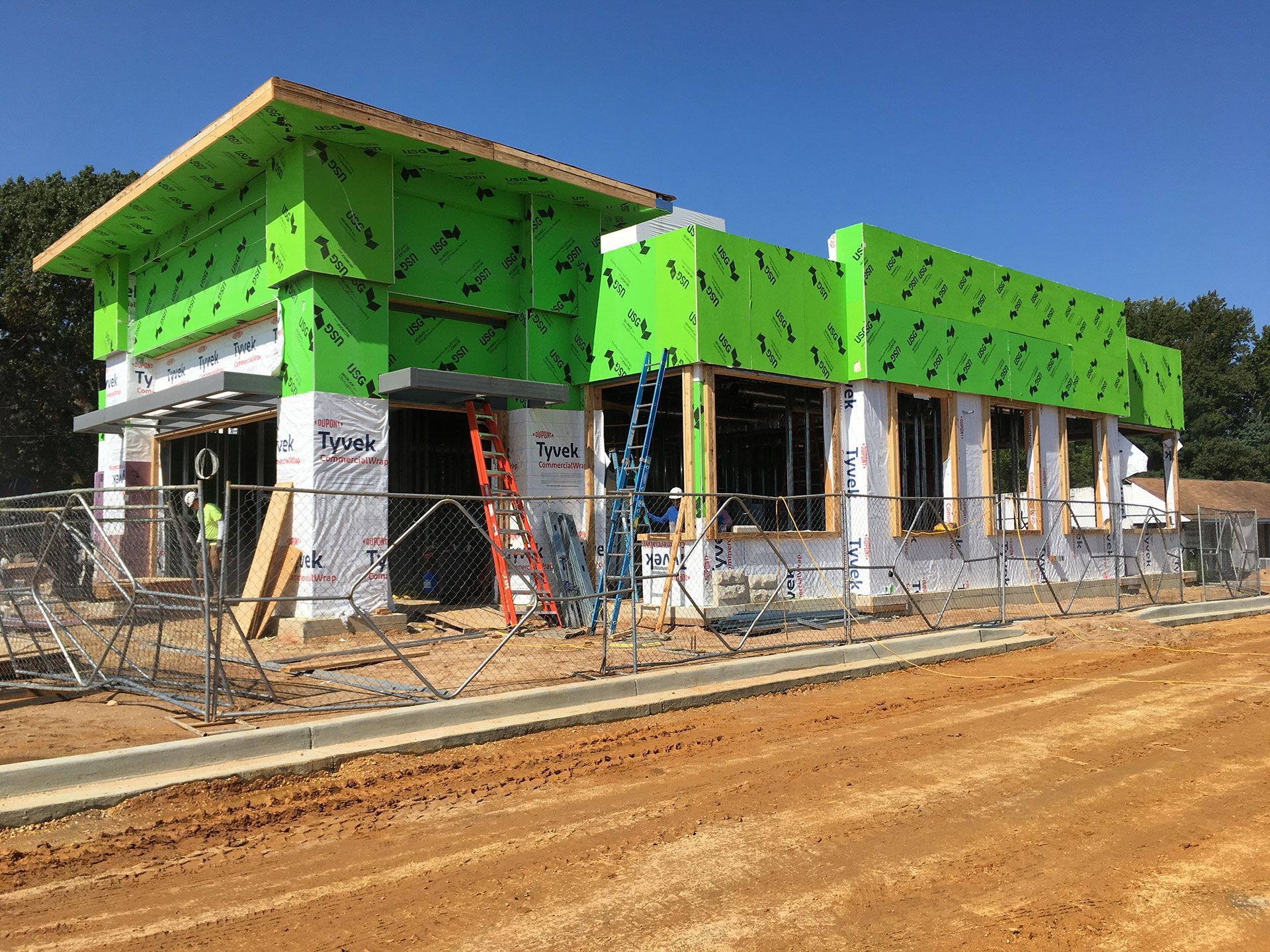 A building is being built with green insulation and a fence around it