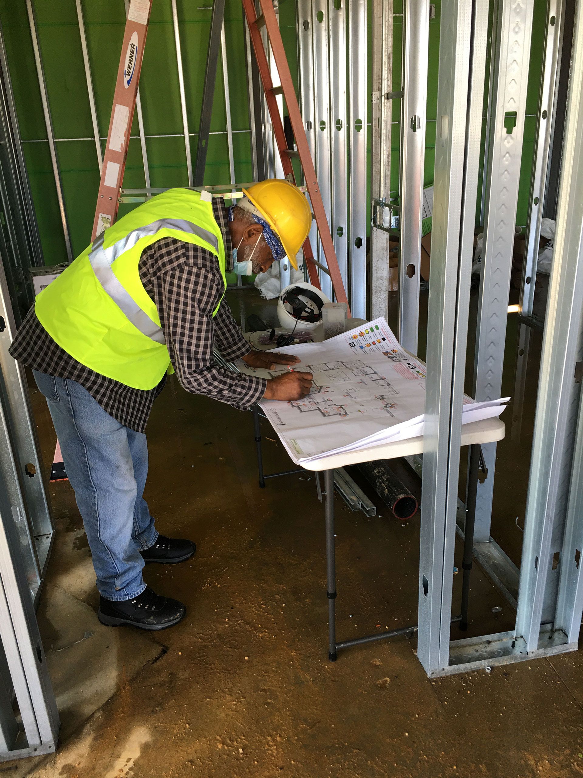 A construction worker is looking at a blueprint on a table