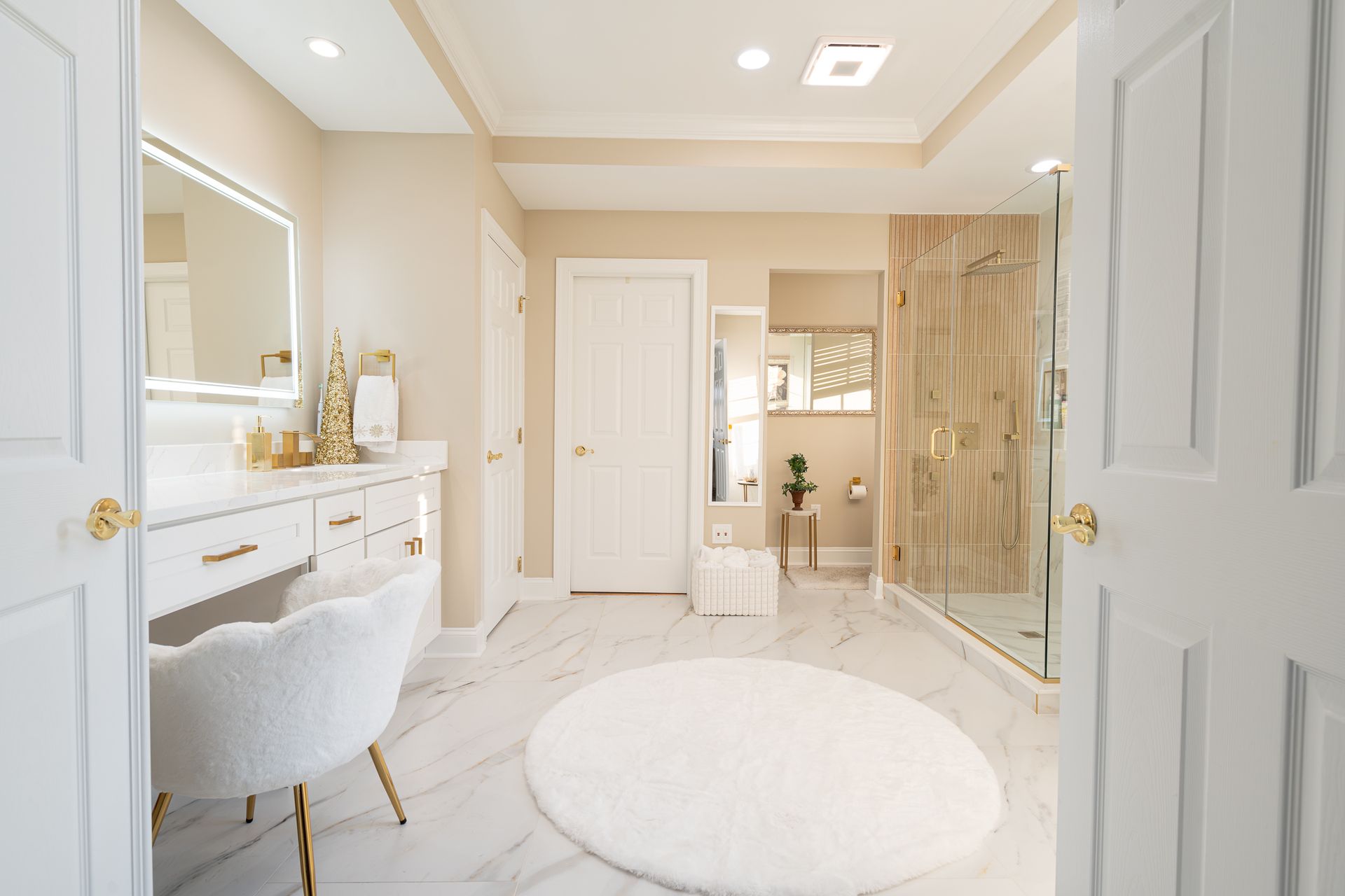 A large bathroom with a walk in shower , vanity , chair and rug.