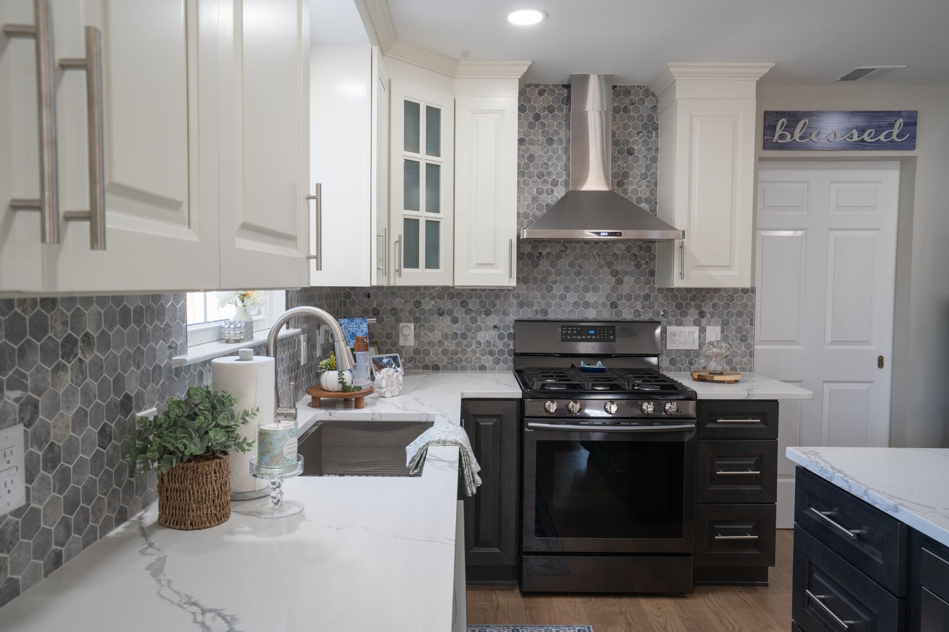 A kitchen with white cabinets, black appliances, a sink, and a stove.