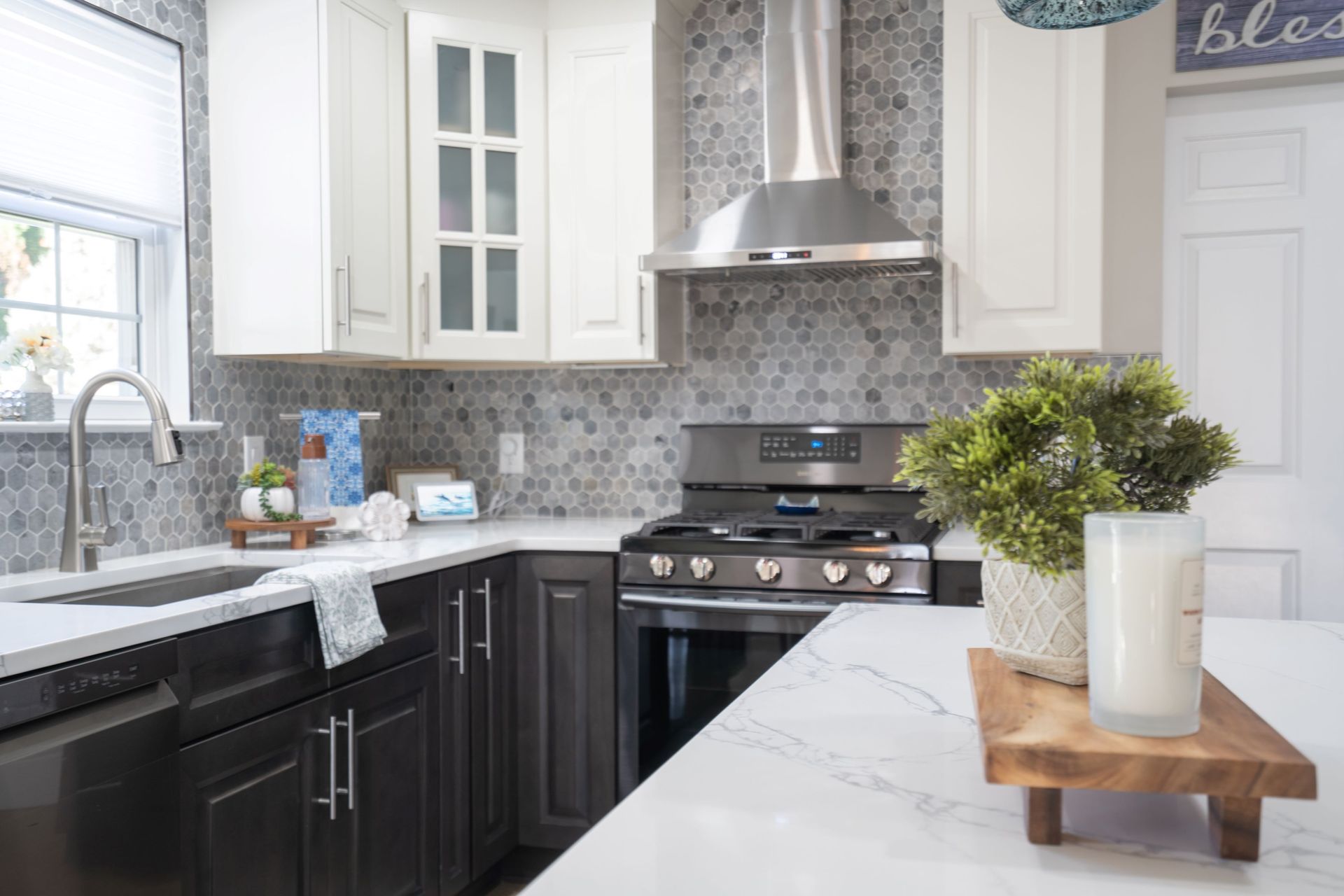 A kitchen with stainless steel appliances, gray cabinets, white countertops, and a stove.