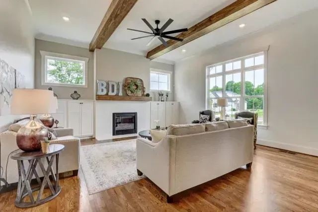 A living room with a couch, chairs, a fireplace and a ceiling fan