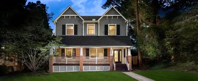 A large house with a large porch is lit up at night