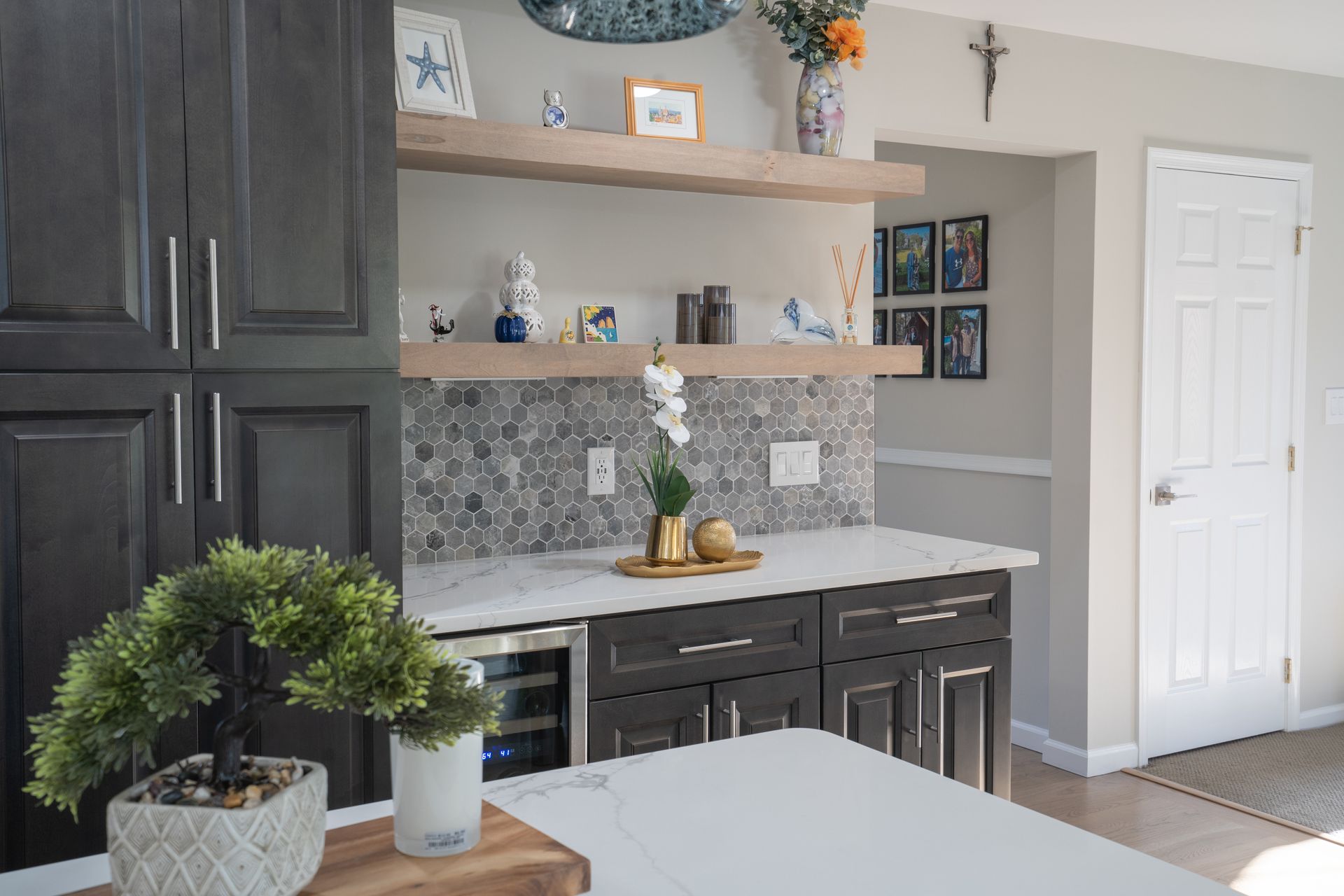 A kitchen with black cabinets, white countertops, and a refrigerator.