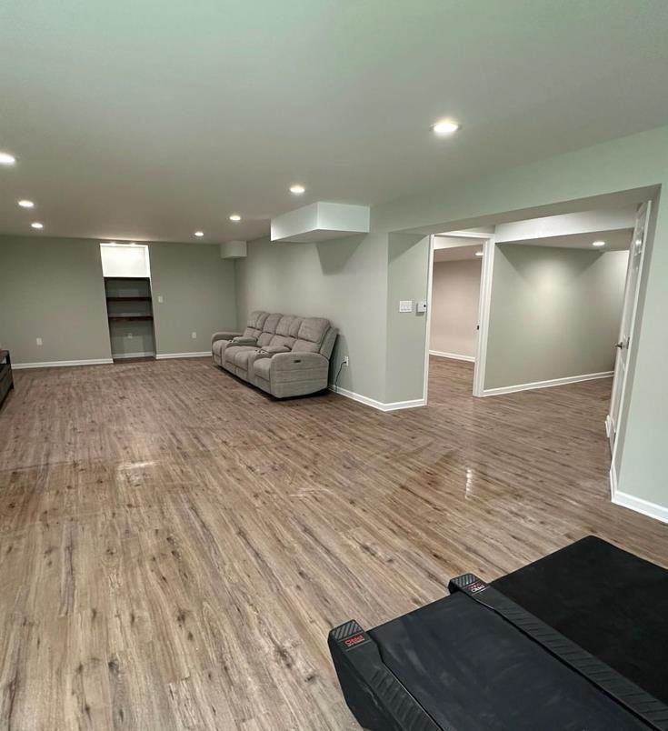 A basement room with hardwood floors and a couch