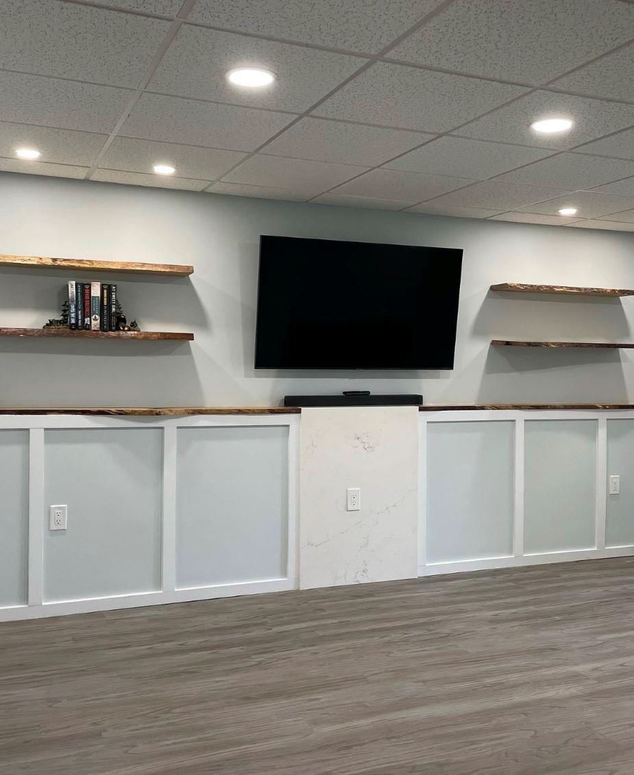 A basement room with a flat screen tv on the wall