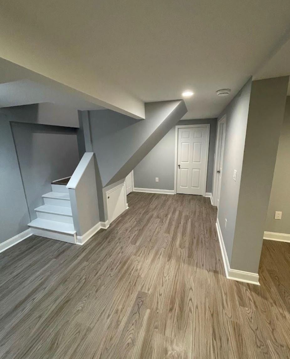An empty basement with hardwood floors and stairs