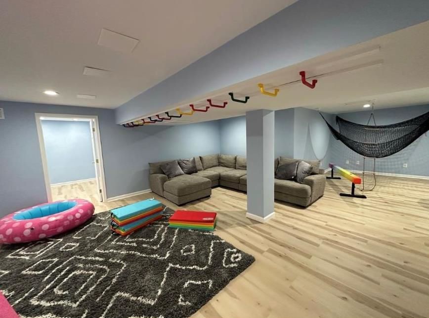A basement with a couch, hammock, and a rug