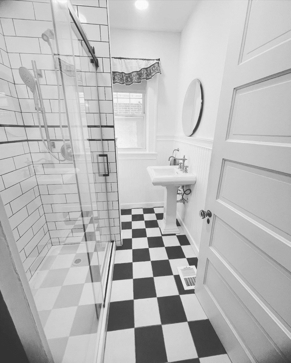 A black and white photo of a bathroom with a checkered floor