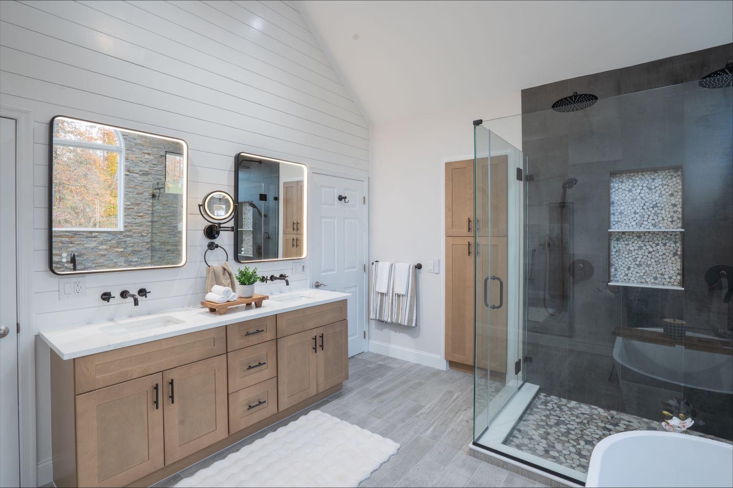 A bathroom with two sinks , a tub , and a walk in shower.