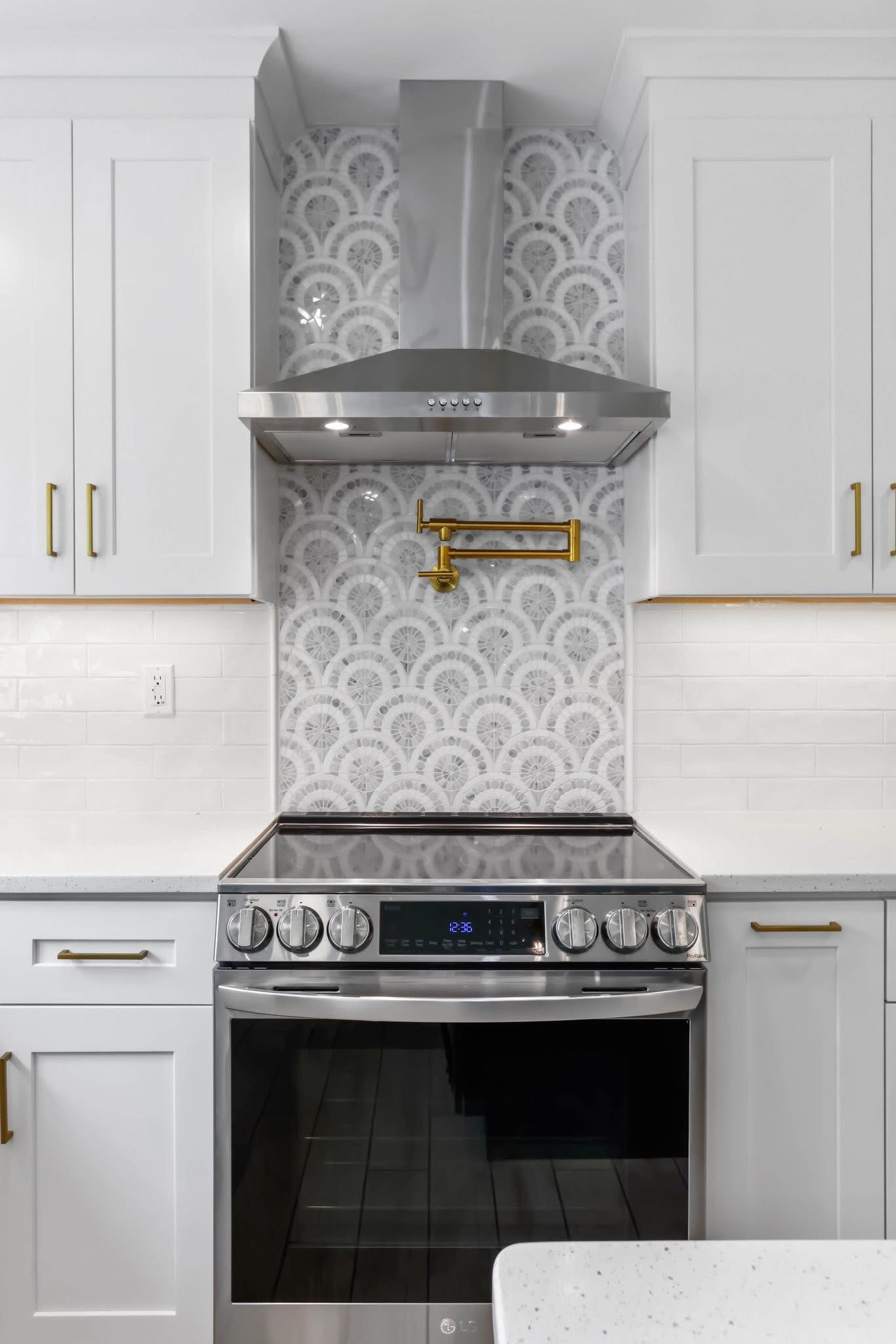 A kitchen with white cabinets , a stove , and a hood.