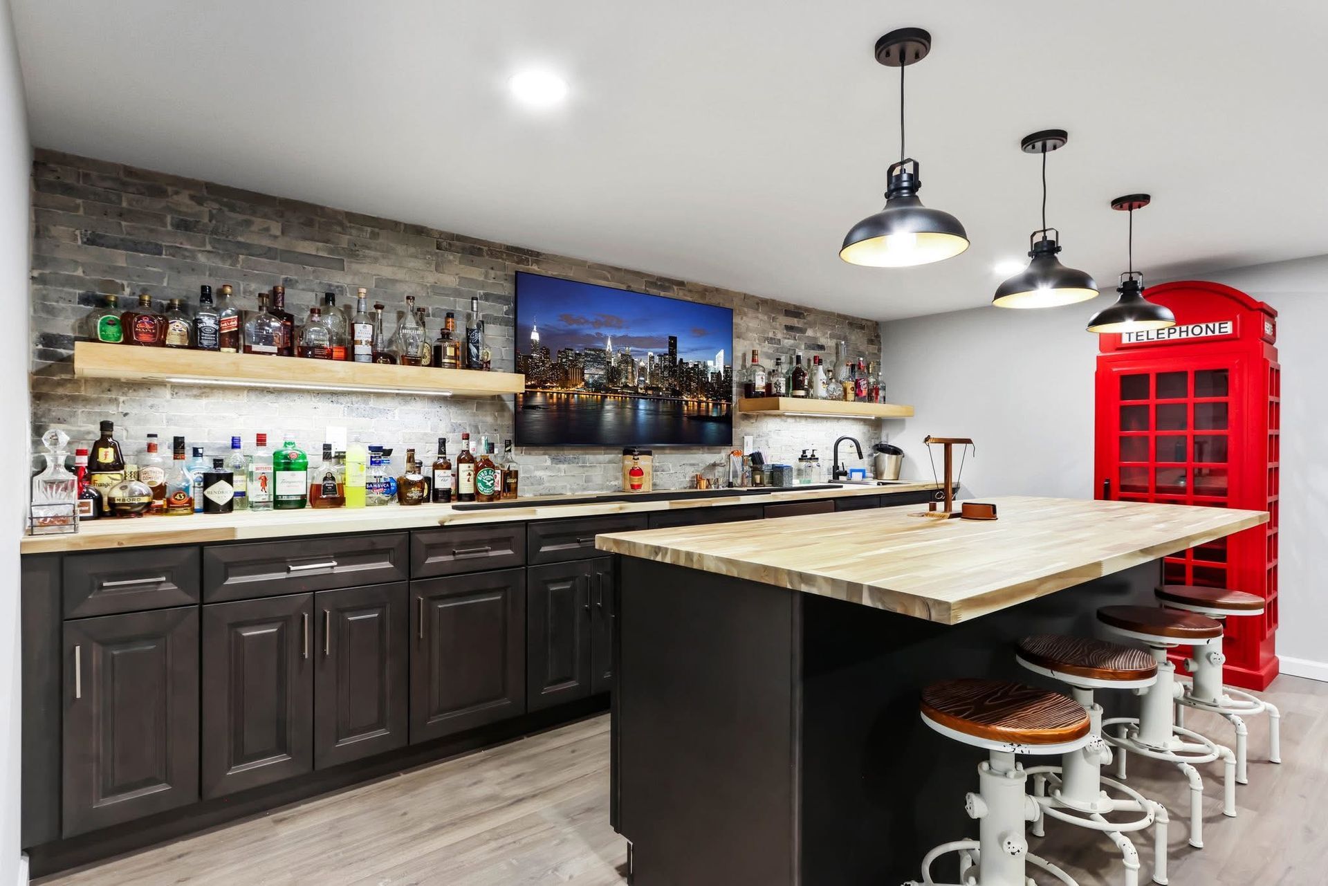A basement bar with a large island and a red telephone booth.