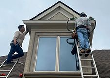 Two men are working on the roof of a house.