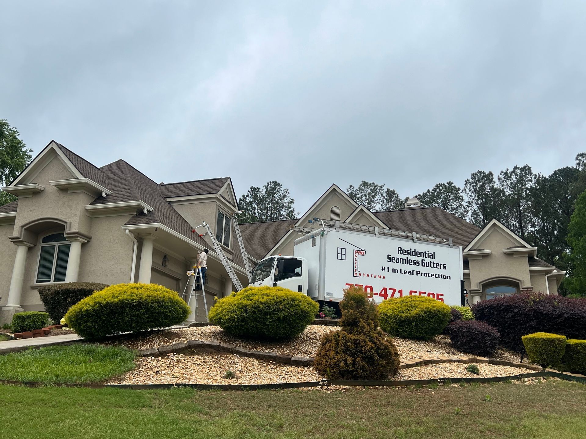 A white truck is parked in front of a large house.