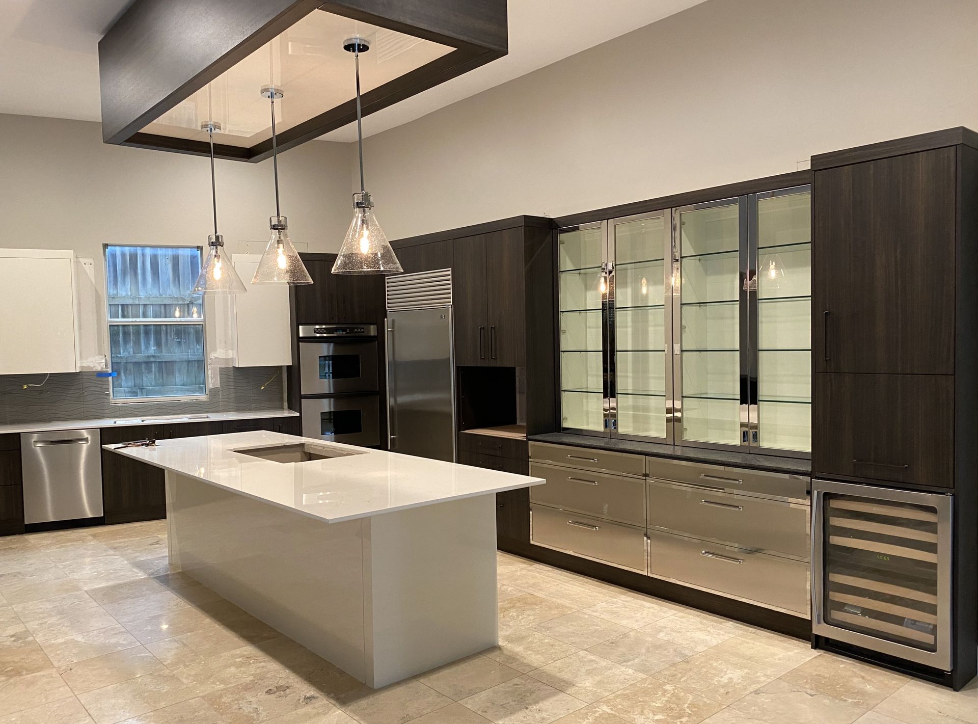 Modern kitchen with dark wood cabinetry, stainless steel appliances, and white island.