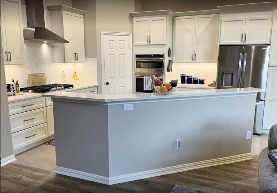 Modern kitchen with white cabinets, gray island, and stainless steel appliances.