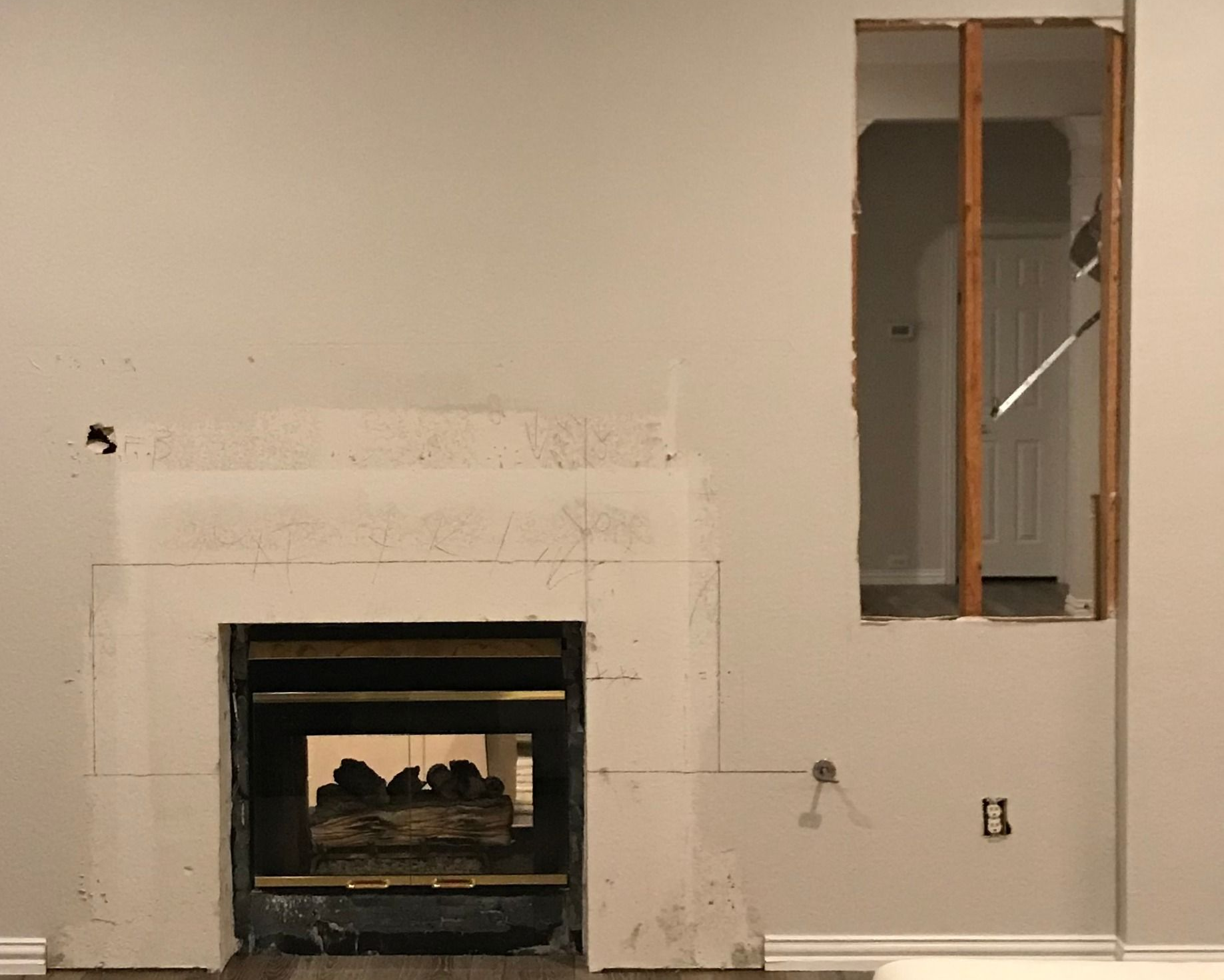Fireplace with drywall removed, showing the firebox and a partially framed opening.