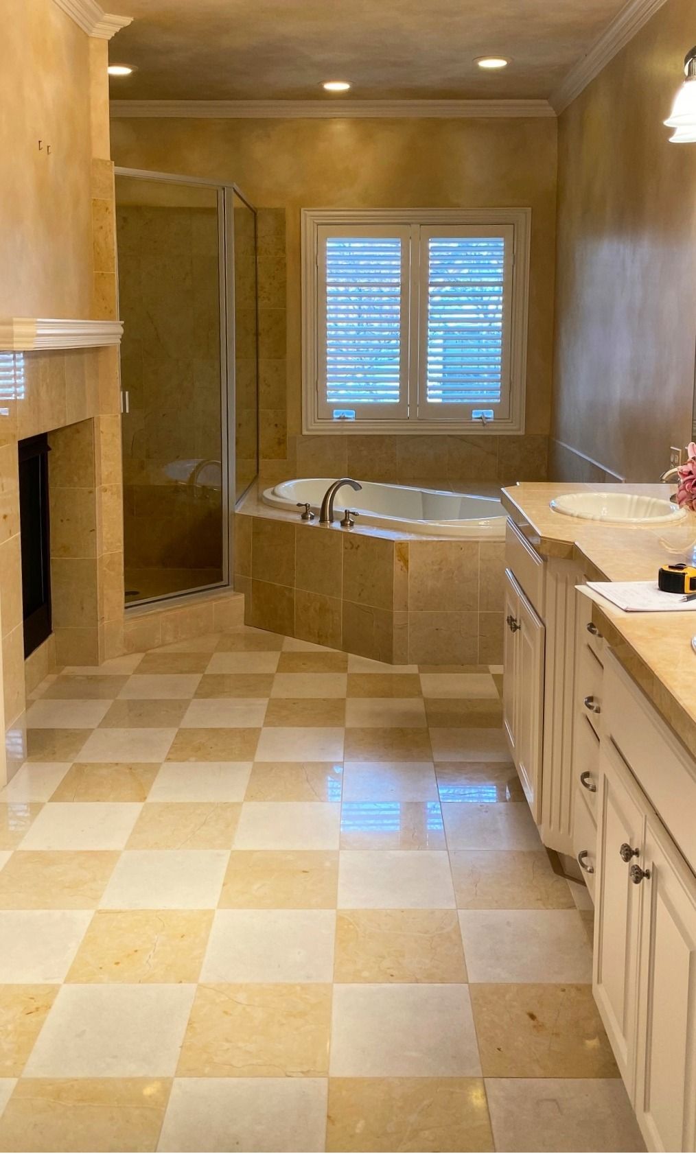 Bathroom with checkered tile floor, bathtub, shower, vanity, and a window with closed shutters.