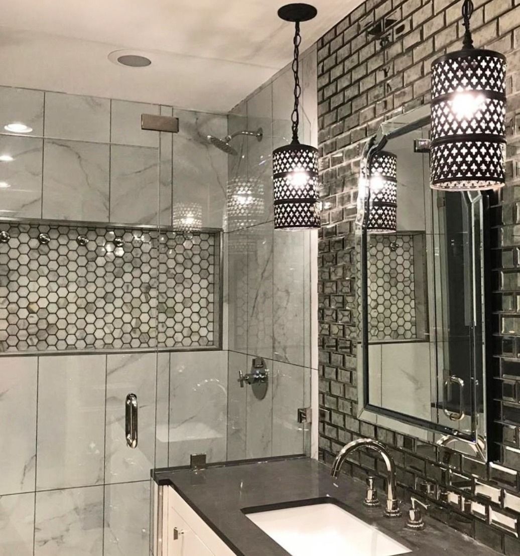 Modern bathroom with marble and mirrored tile, two pendant lights, and a glass shower.
