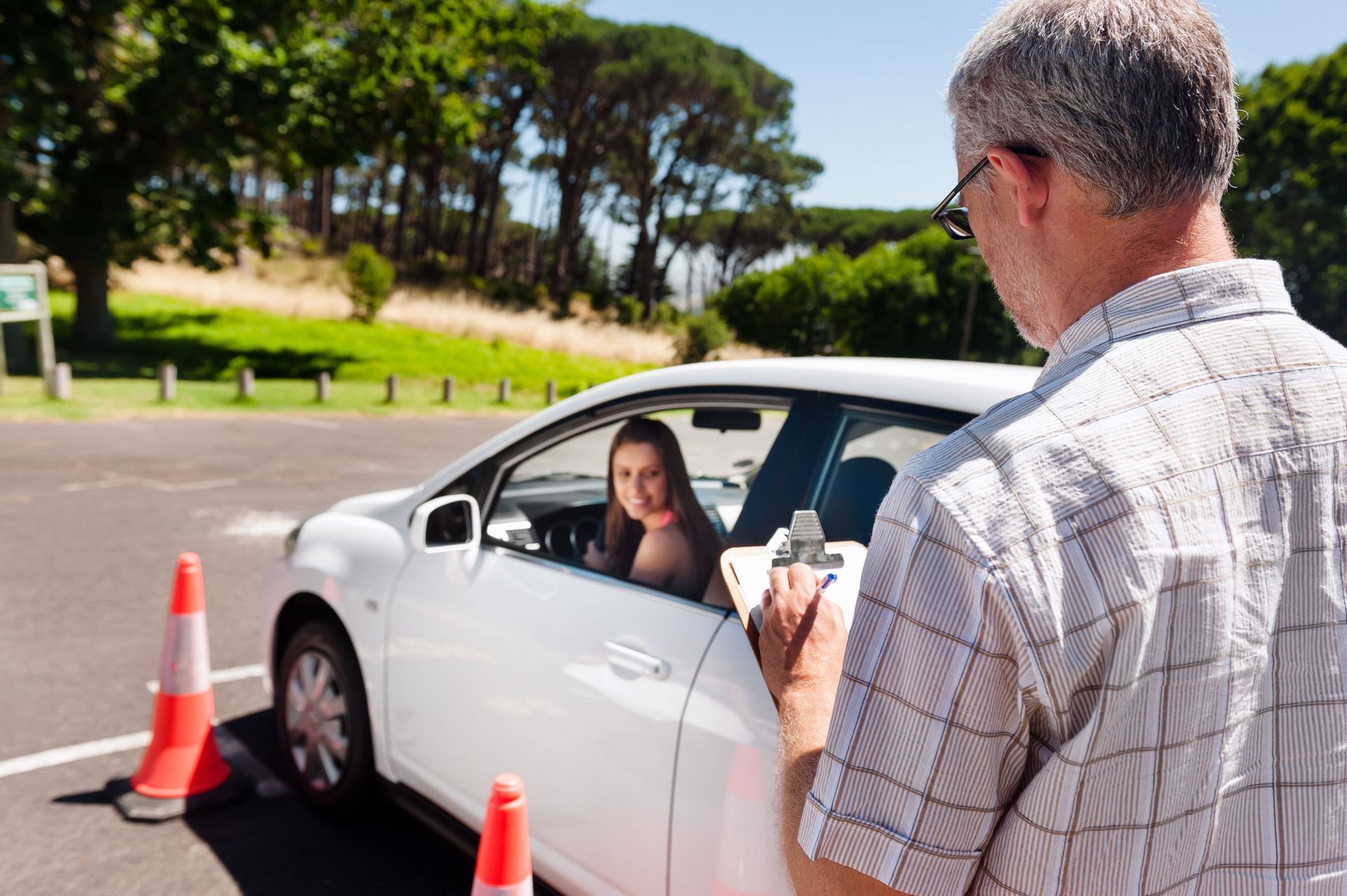 Driver stopped at a roadside checkpoint, speaking to a man with a clipboard beside traffic cones.