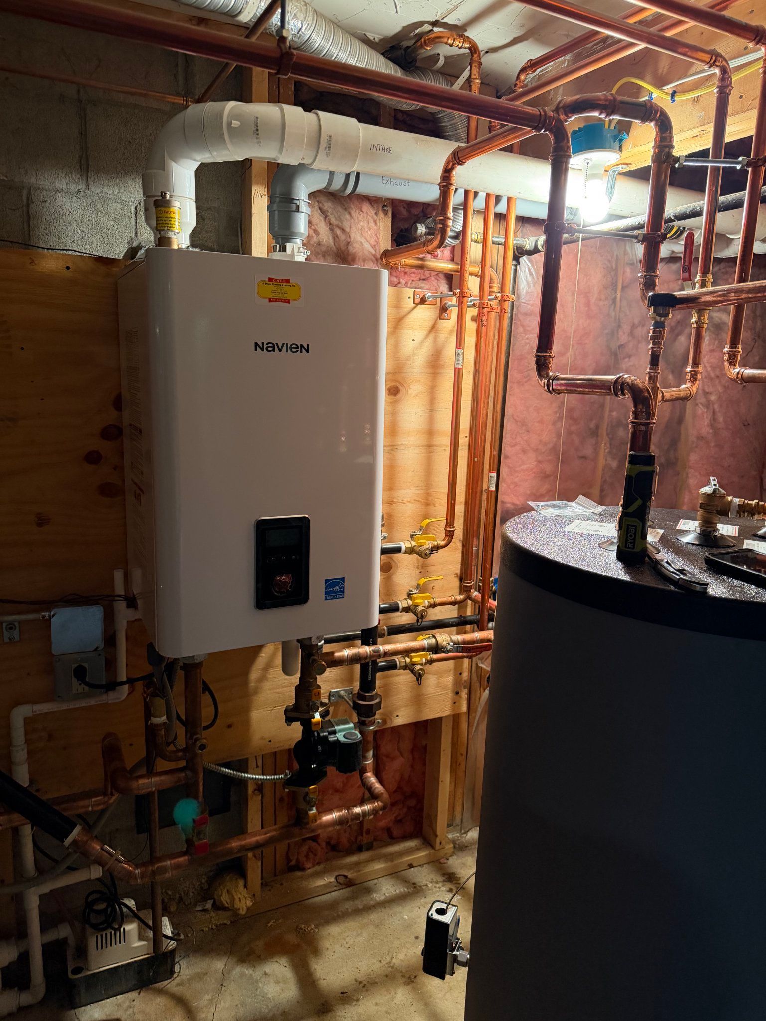 Utility room with white wall-mounted boiler, copper pipes, and a black cylindrical tank.