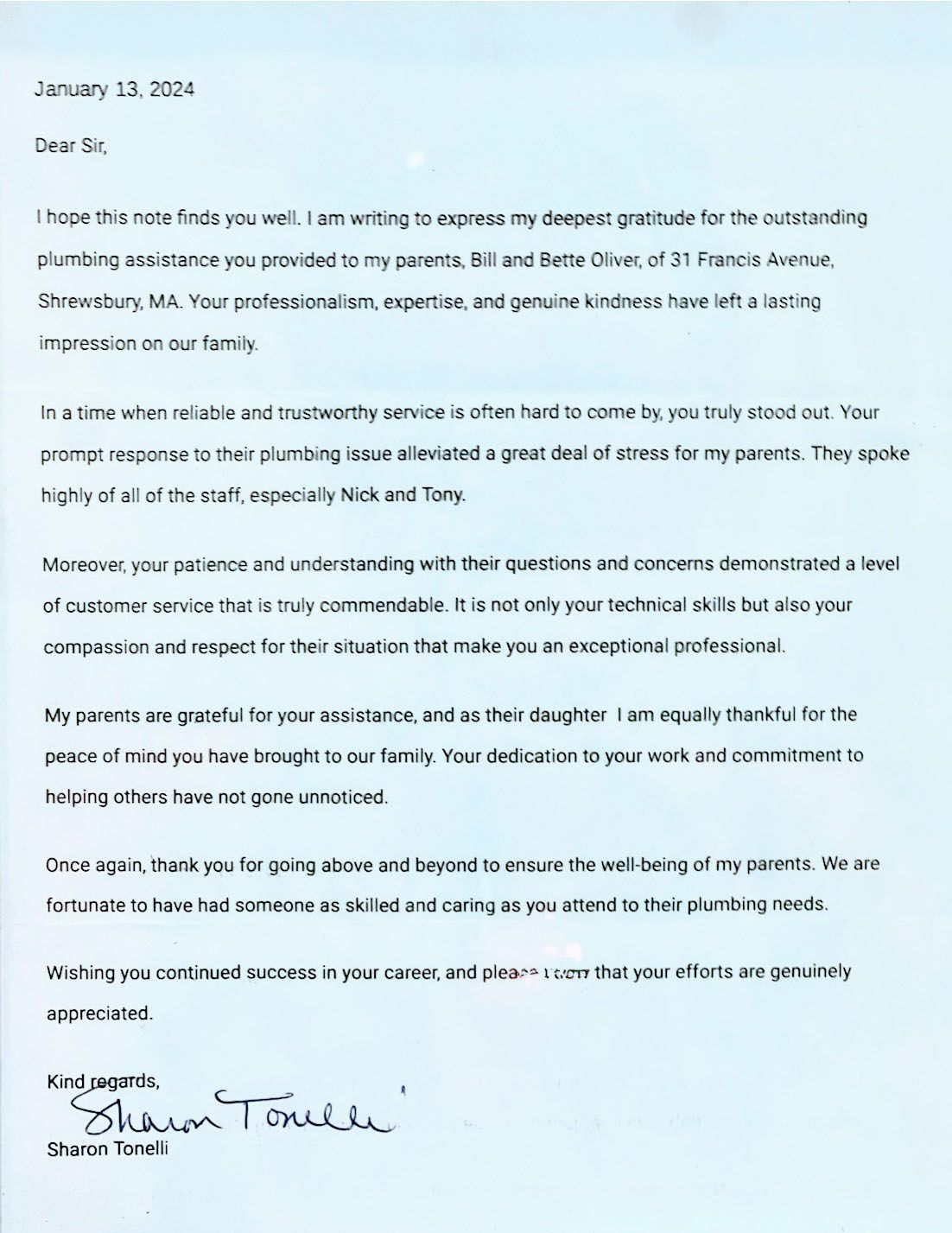Blurry photographed typed letter on white paper with a handwritten signature at the bottom.