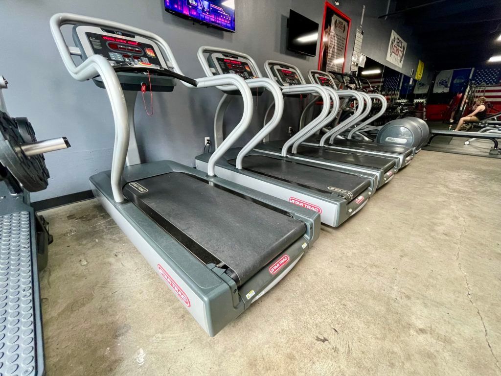 A row of treadmills are lined up in a gym.
