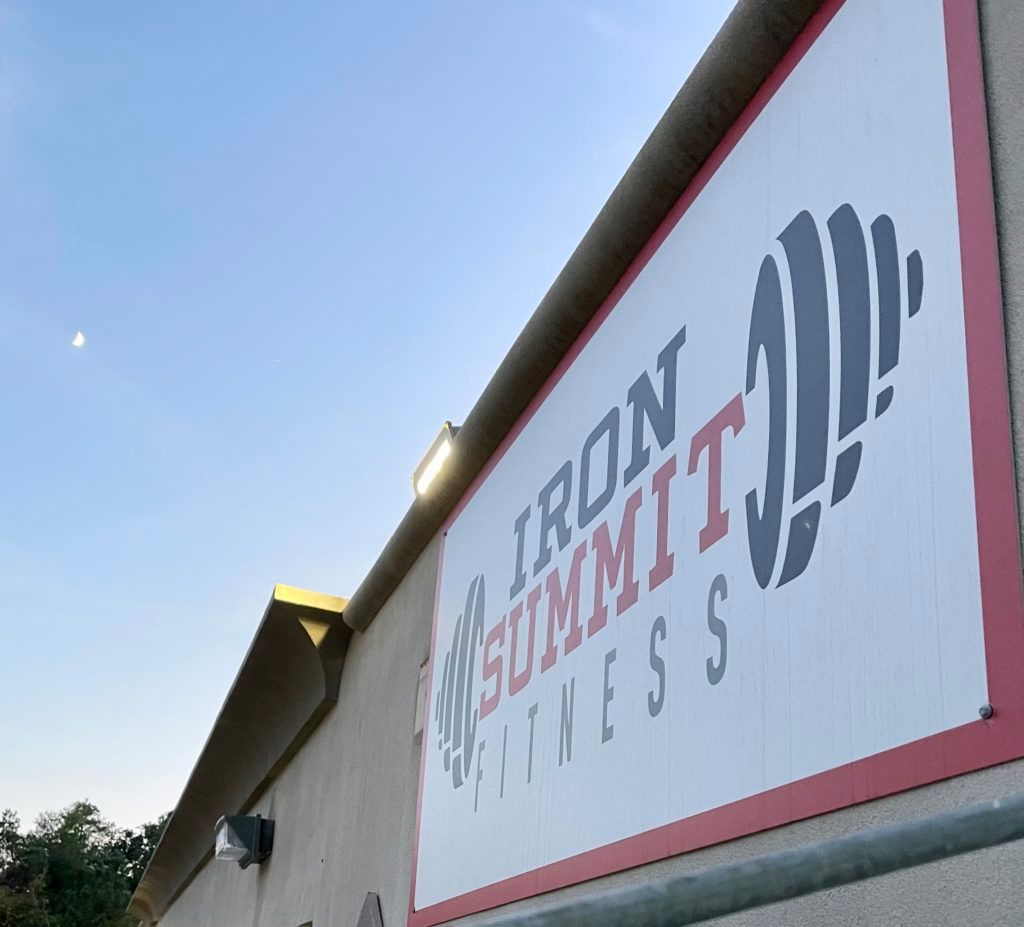 A sign on the side of a building that says iron summit fitness
