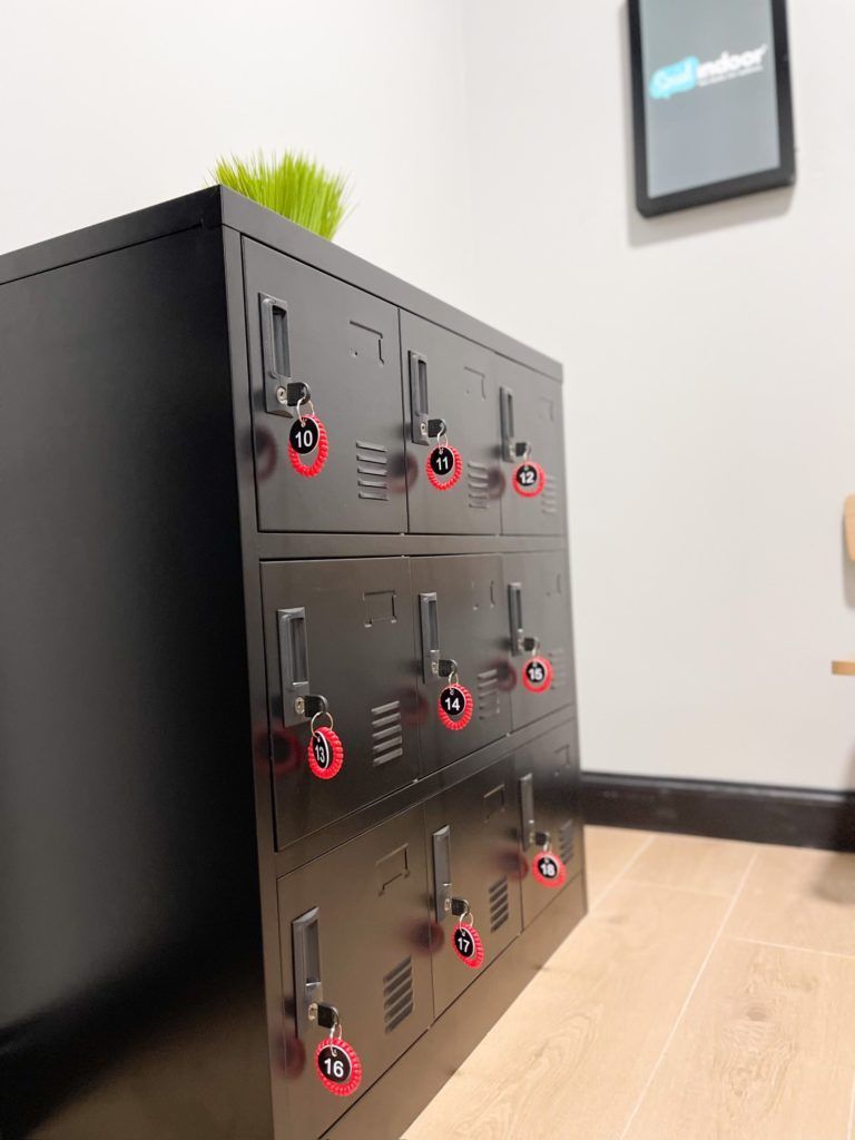 A row of black lockers with red keys in a room.