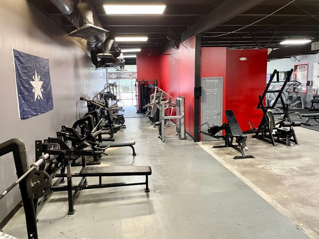 A gym filled with lots of exercise equipment and a flag on the wall.