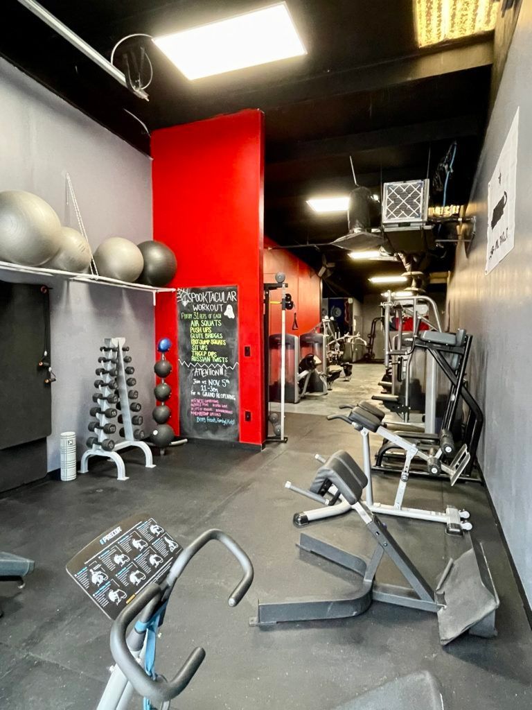 A gym with a lot of equipment and a red wall.