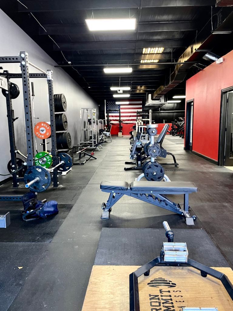 A gym with a lot of exercise equipment and an american flag on the wall.