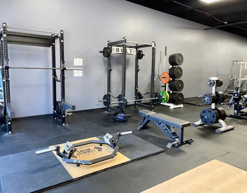 A gym filled with lots of exercise equipment and a bench.
