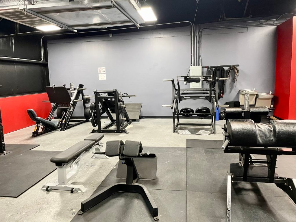 A gym filled with lots of exercise equipment and a bench.