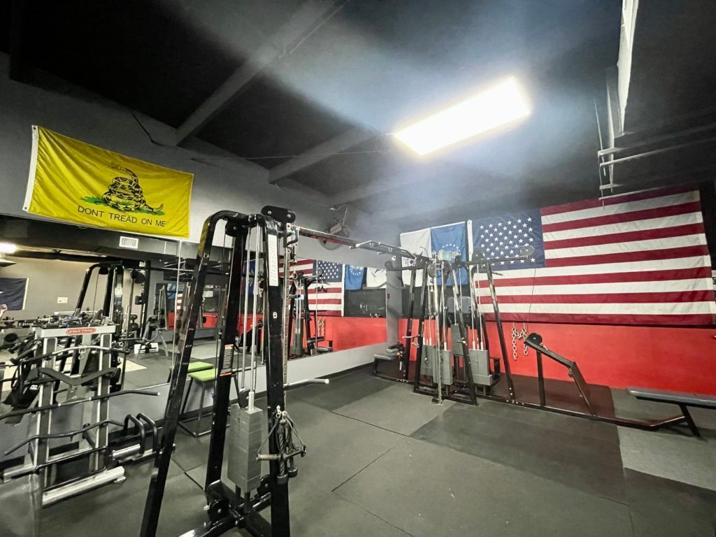 A gym with a lot of exercise equipment and a flag on the wall.