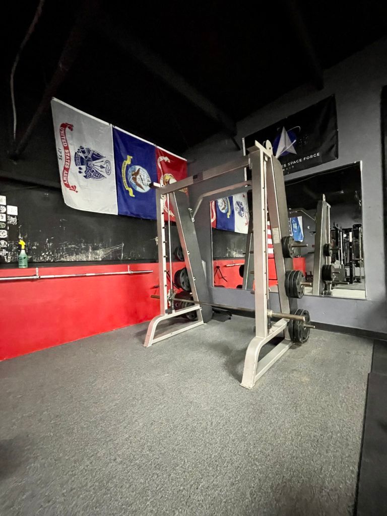 A gym with a lot of equipment and flags on the wall.