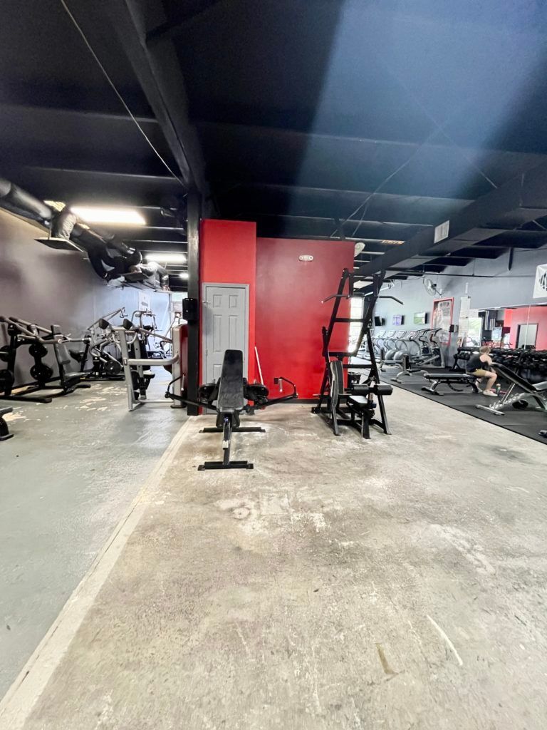 A gym filled with lots of exercise equipment and a bench.